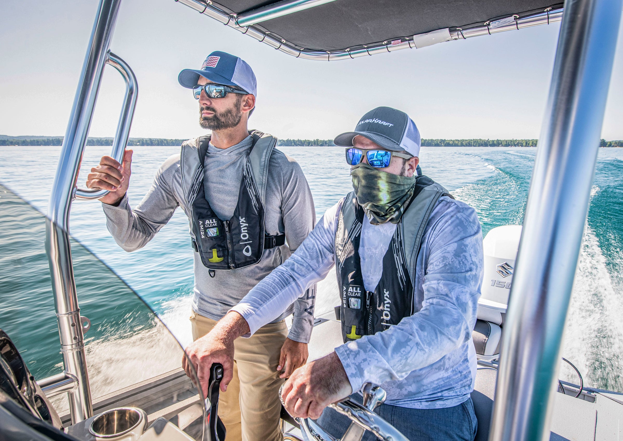 Two fishermen wearing Onyx inflatable Life Vests on a boat heading out to the open ocean to fish.